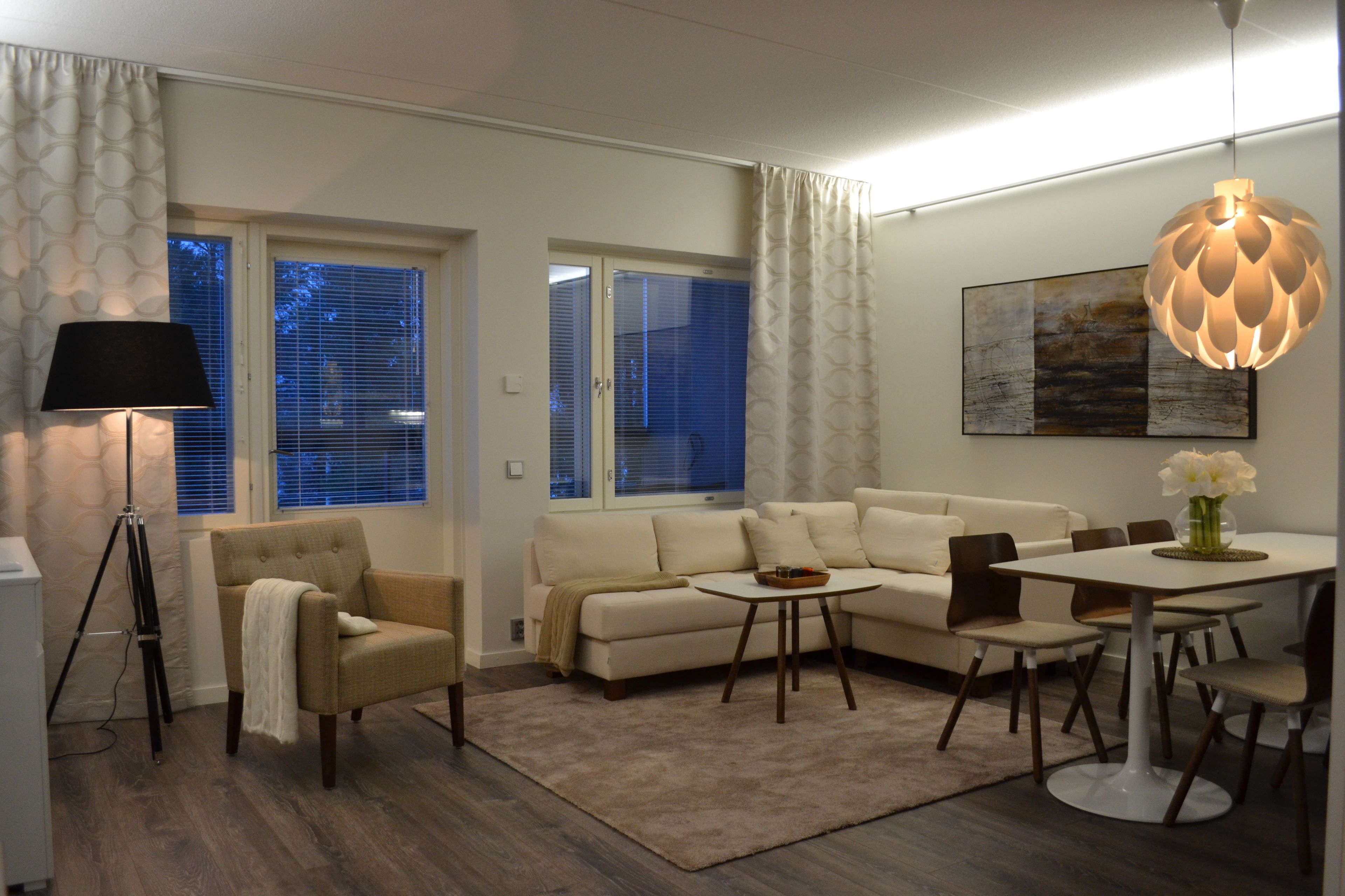 Una sala de estar moderna con sofá, sillones, una mesa de comedor y una lámpara.