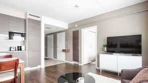 Una sala de estar moderna con comedor, televisor de pantalla plana y cocina equipada con microondas y cafetera.