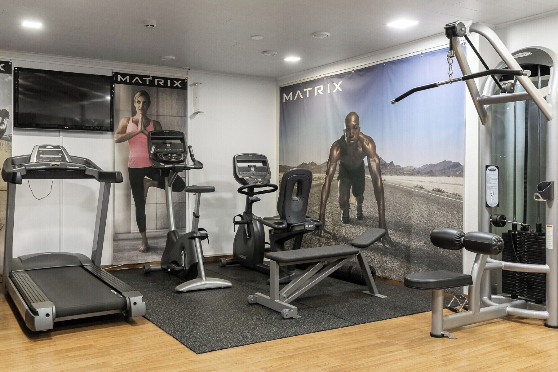 Une salle de sport équipée de tapis de course, de vélos elliptiques et de matériel de musculation.