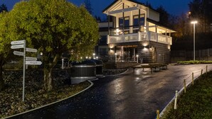Un hotel moderno con estructura de dos pisos, zona de estar al aire libre y un cartel indicador de las diferentes secciones del hotel.