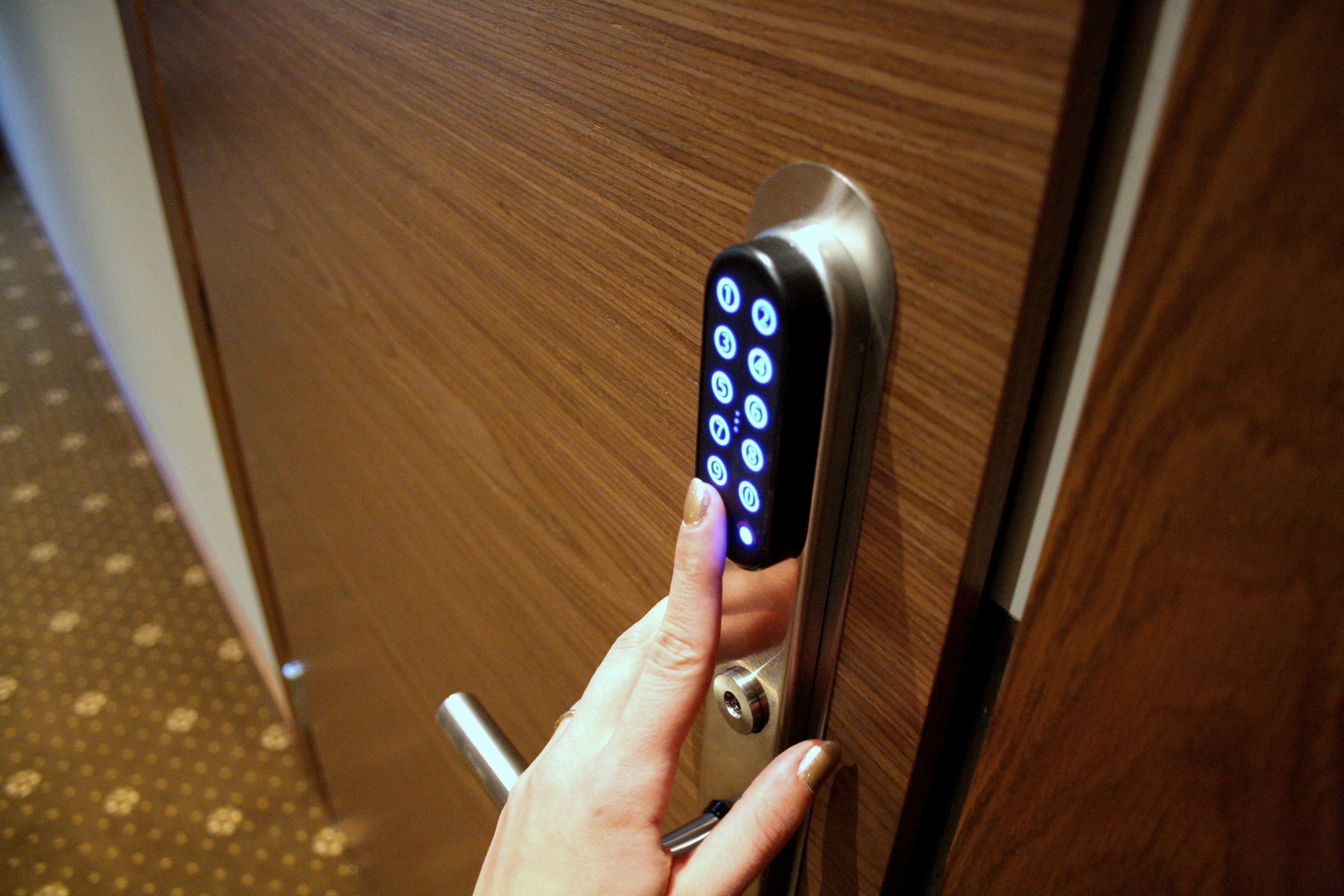 A hand using a numeric keypad on a door lock.