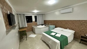 Hotelkamer met een bed, een klein bureau, een stoel, een raam met gordijnen, een wandairconditioner en een bad.