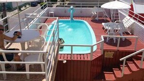 A pool area with a hot tub, white lounge chairs, and a wooden deck. - Pousada Panoramica (Aracaju)