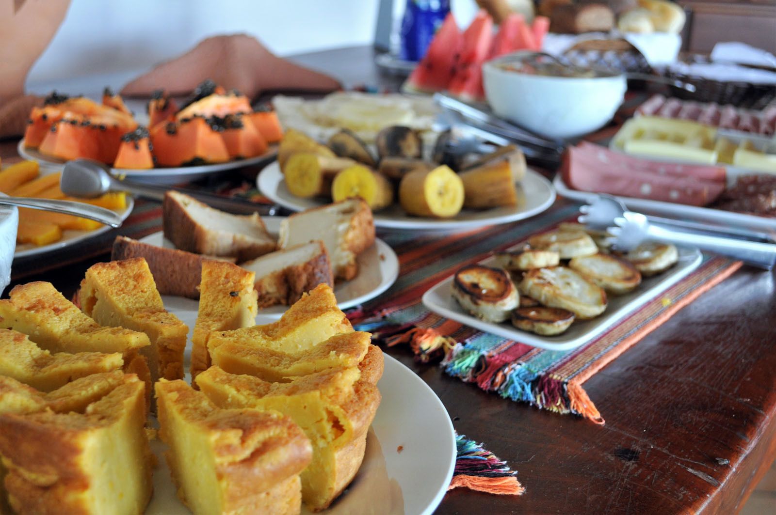 Una mesa con diversos alimentos, como pan, frutas y repostería.