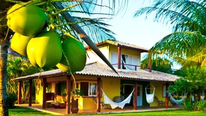 A house with a tiled roof, a porch with seating, and a hammock. - Grimms Pousada de Contos (Entre Rios)