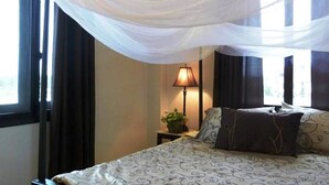 A bedroom with a bed, a nightstand, a lamp, and a window with curtains.