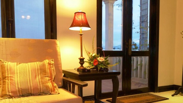 A cozy room with a sofa, a table with a lamp, and a window with a view of buildings.