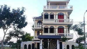 A multi-story building with balconies, arched windows, and a central entrance with a decorative gate.