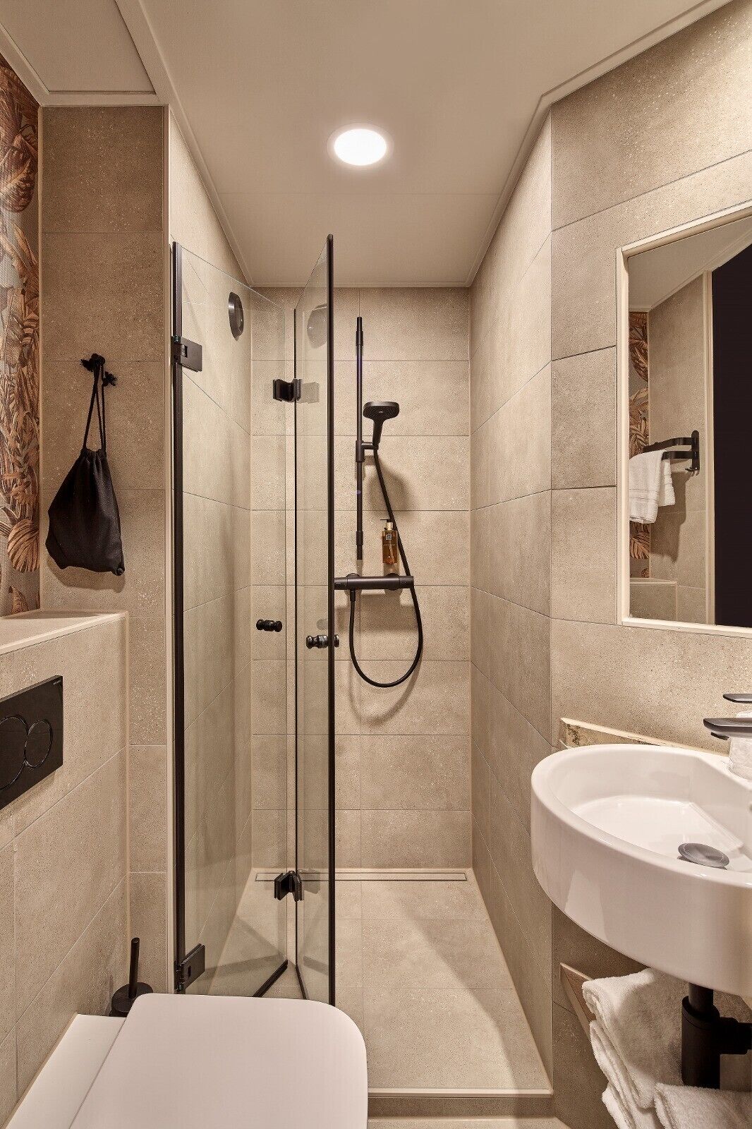 A modern bathroom with a glass-enclosed shower, a white sink, and a large mirror.