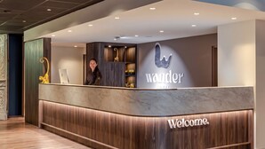 A reception desk with a 'Welcome' sign, a 'Wander Hotel' sign, and a golden statue. - Hotel Wander (Wageningen)