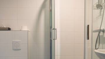 A bathroom with a glass-enclosed shower, a toilet, and a white sink.