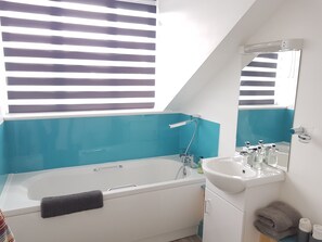 Romantische tweepersoonskamer | Badkamer | Een bad/douchecombinatie, gratis toiletartikelen, een haardroger