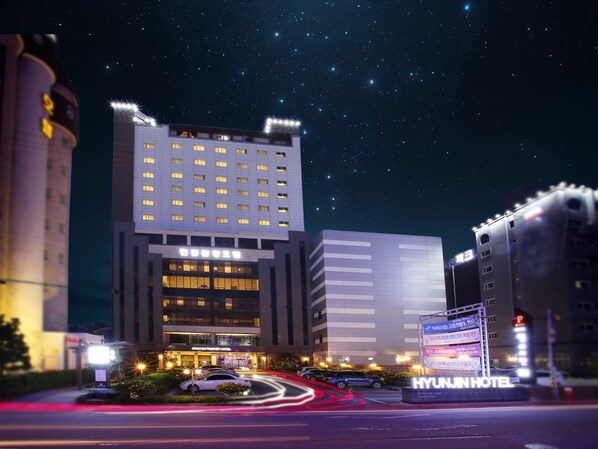 A modern hotel with a prominent entrance, multiple floors, and a well-lit facade.