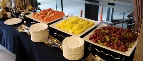 Una mesa de buffet con diversas frutas y un dispensador de agua.
