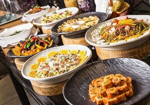 A variety of dishes on a buffet table with different types of food and garnishes.
