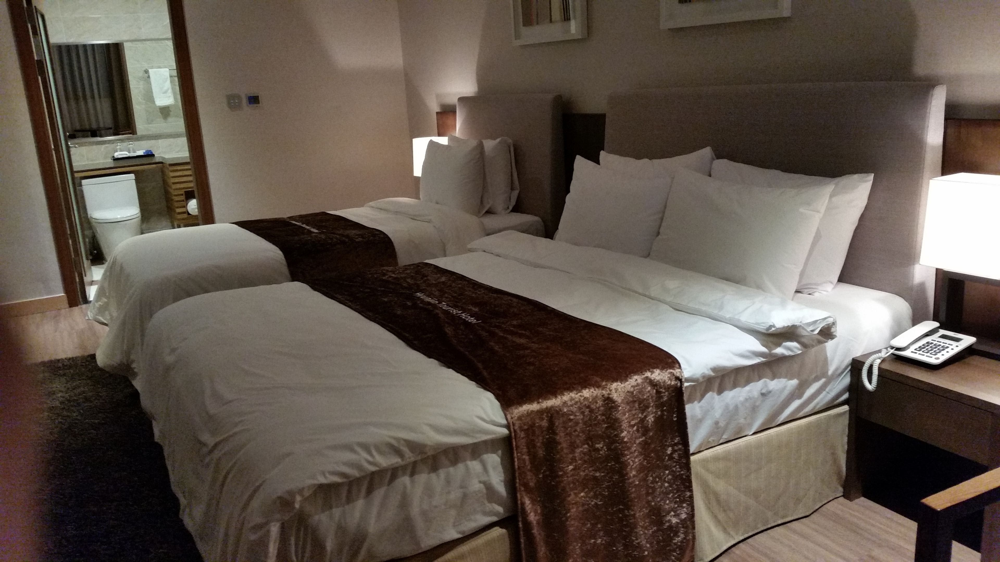 A hotel room with two beds, a bedside phone, and a mirror.