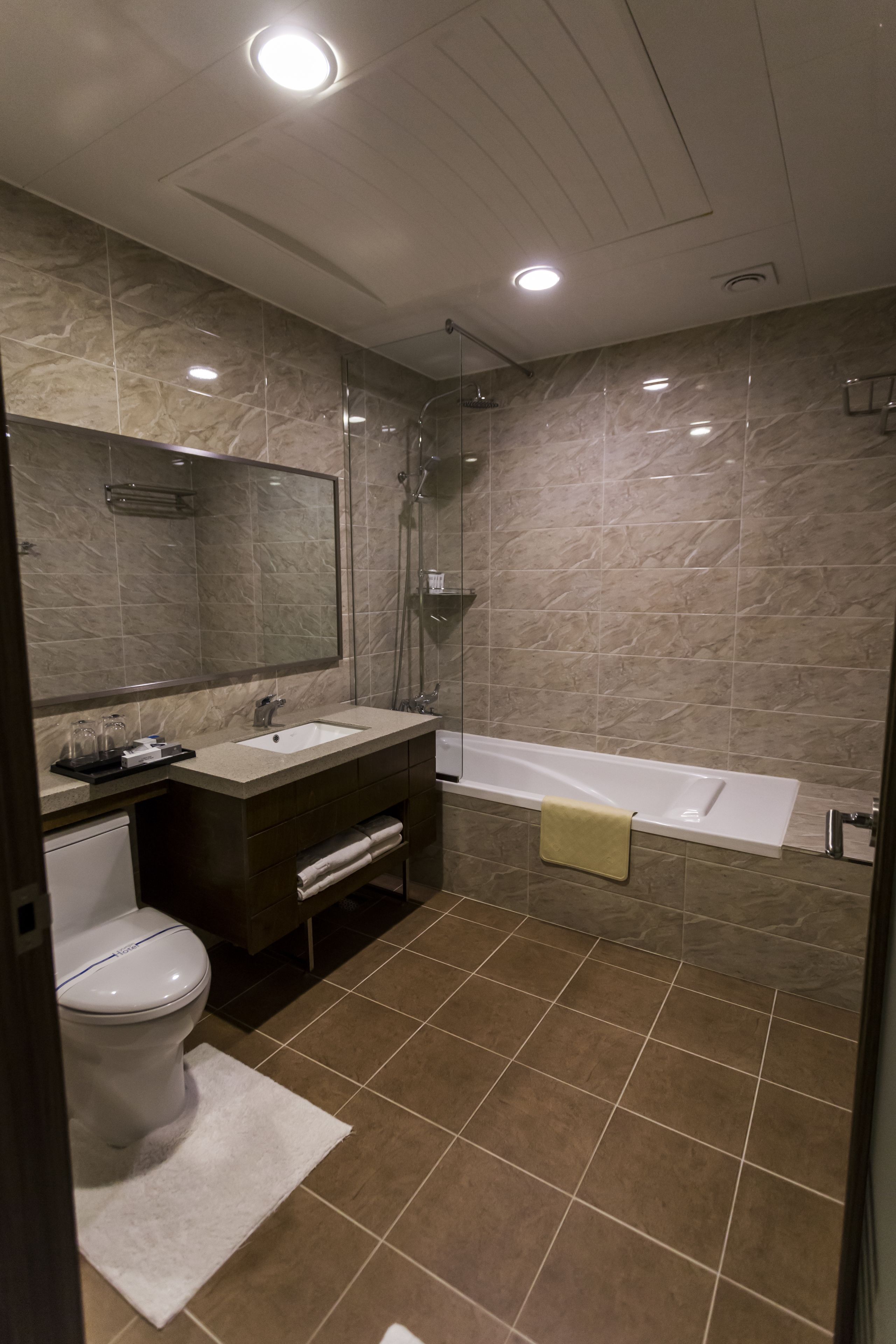 Une salle de bain moderne avec un grand miroir, un lavabo, des toilettes et une baignoire.