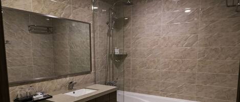 Une salle de bain moderne avec un grand miroir, un lavabo, des toilettes et une baignoire.