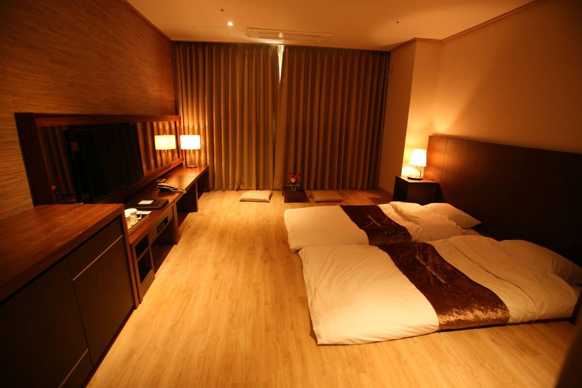 Una habitación de hotel con una cama grande, mesitas de noche con lámparas, un escritorio y un espejo.