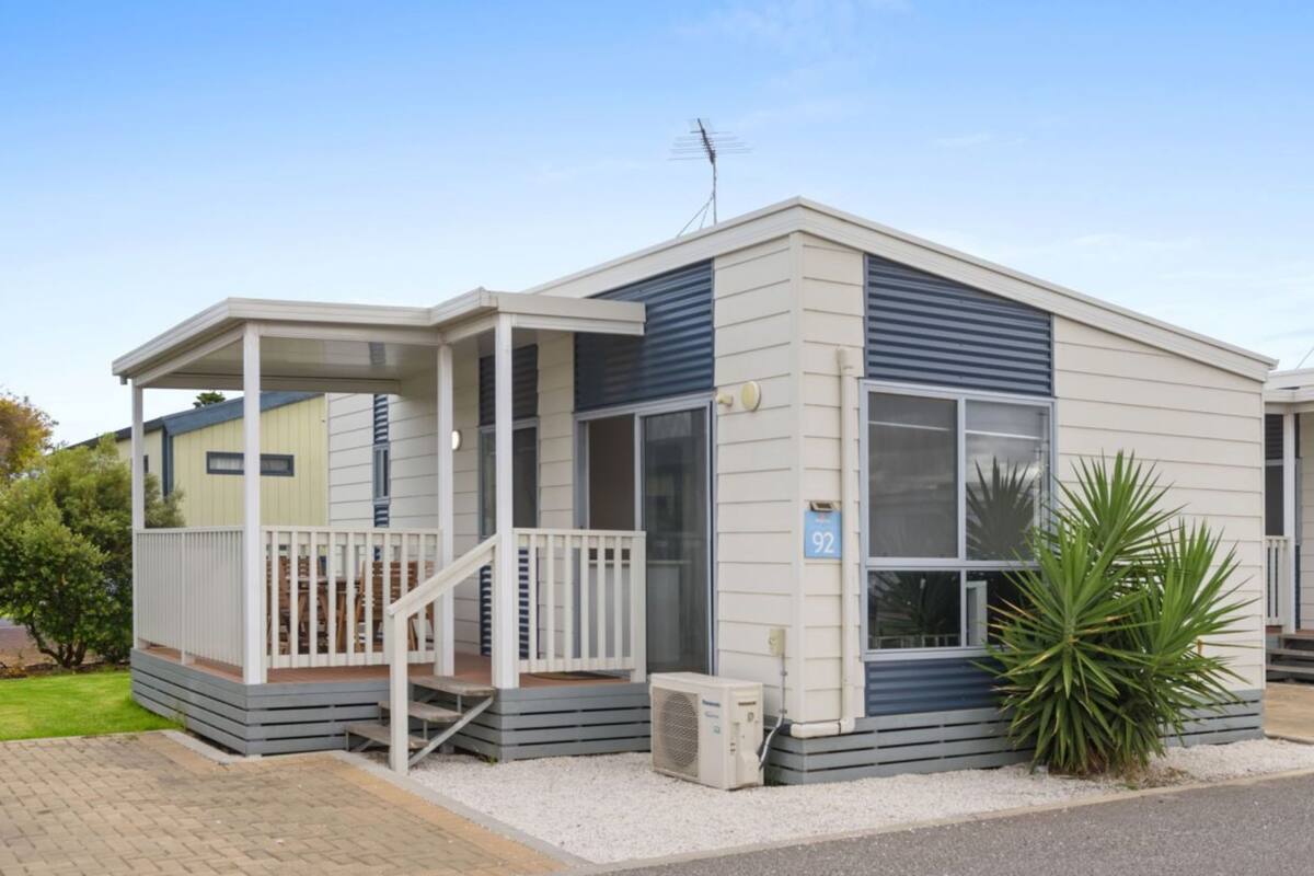 A single-story mobile home with a covered porch and a small front yard.