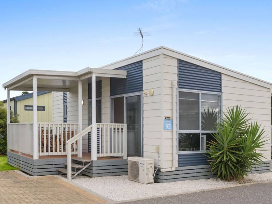 A single-story mobile home with a covered porch and a small front yard.