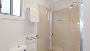 A modern bathroom with a glass shower enclosure, a toilet, and a towel rack.