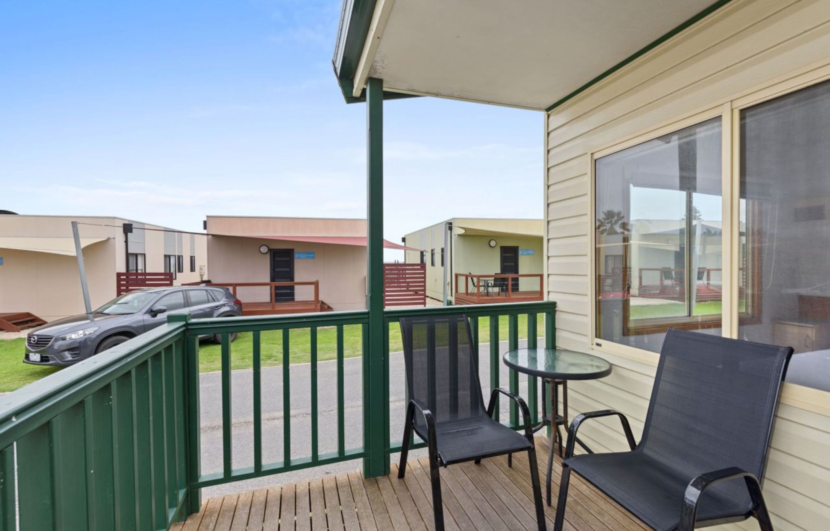 A covered outdoor area with a wooden deck, two chairs, and a table.