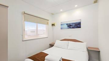 Ein Hotelzimmer mit Bett, Fenster mit Blick, einem Bild an der Wand und einem Thermostat.