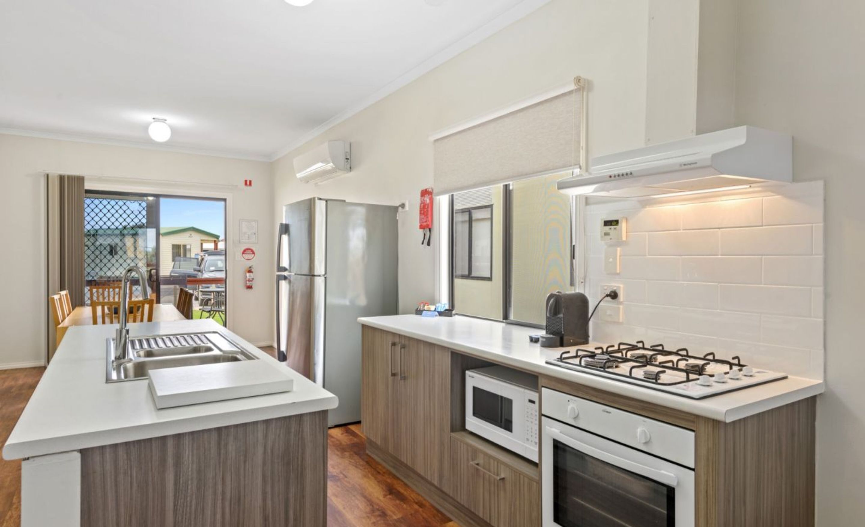 A modern kitchen with a central island, a built-in oven, a microwave, and a gas stove.