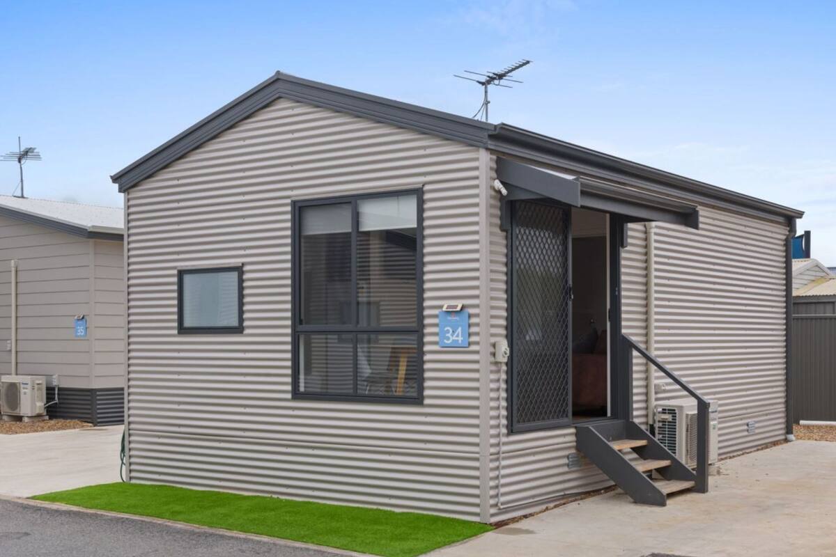A single-story mobile home with a metal exterior, a small front porch, and a staircase leading to the entrance.