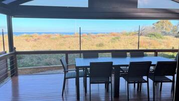 An outdoor deck with a table and chairs, overlooking a coastal landscape.