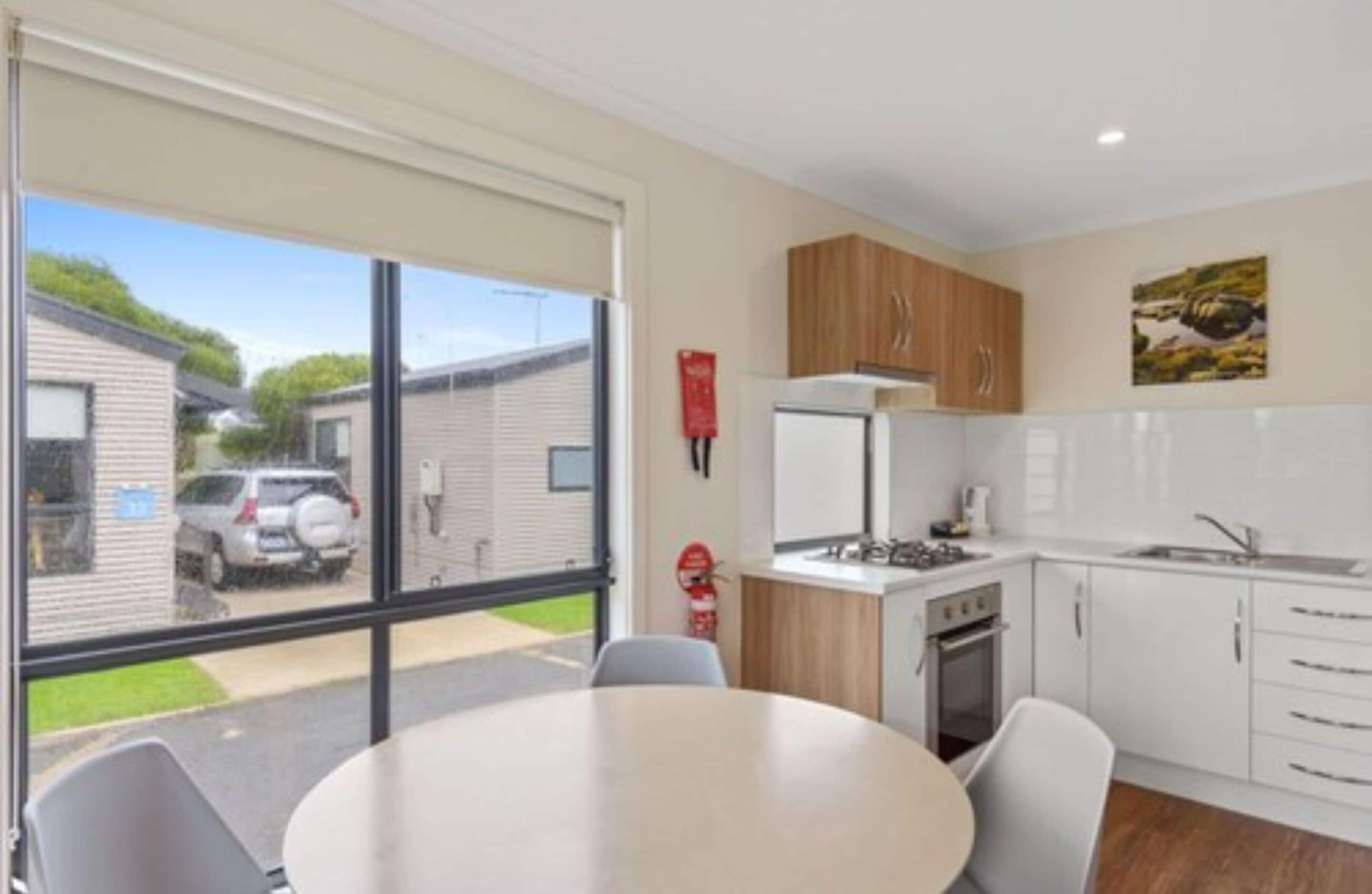 A modern kitchen with white cabinets, a gas stove, and a large window overlooking a residential area.