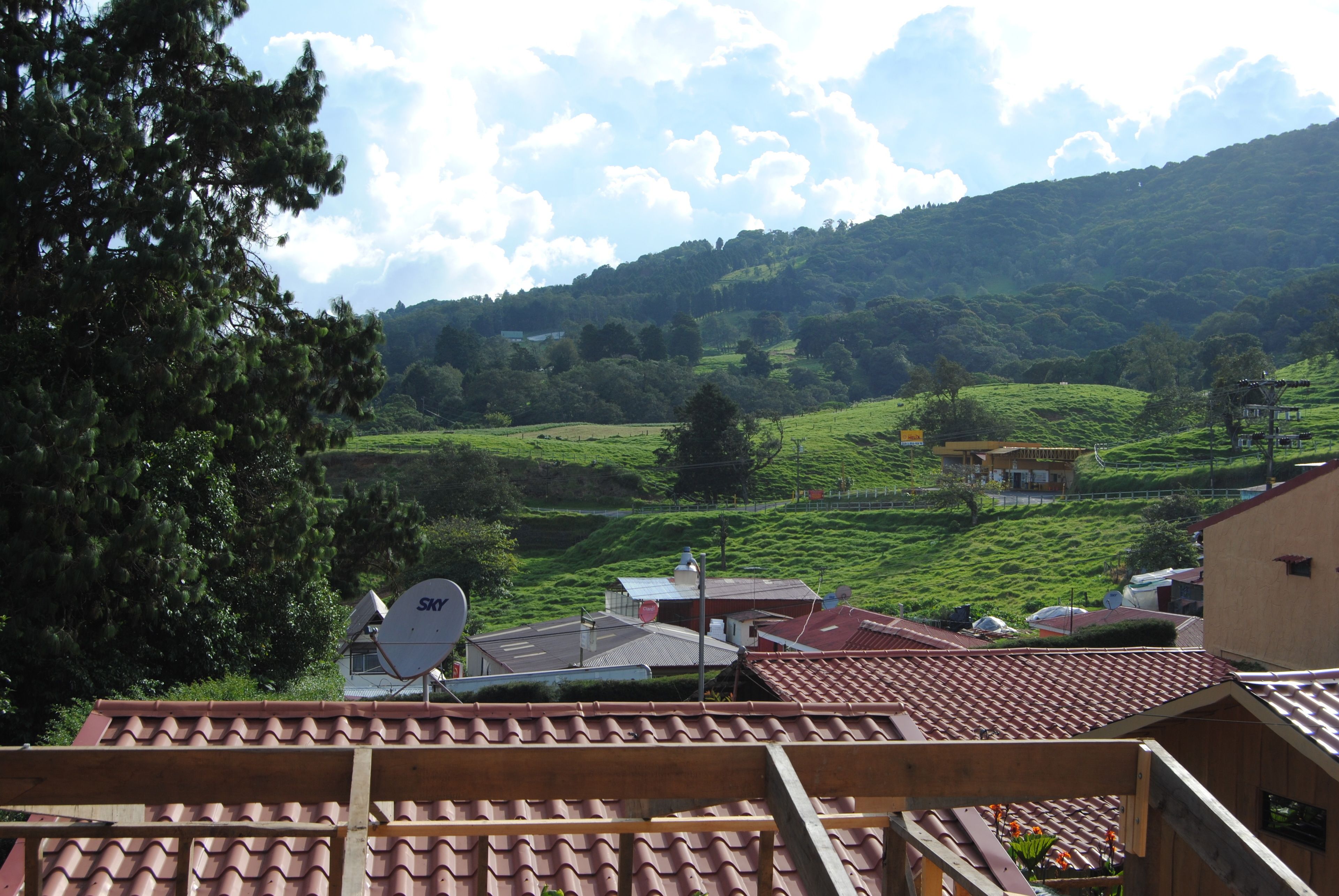 Vista de un valle verde con una casa y una antena parabólica en el tejado.