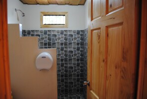 Une salle de bain avec un mur en pierre, une fenêtre et des meubles en bois.