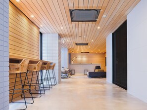 Un moderno vestíbulo de hotel con paneles de madera en el techo, una recepción y zonas de estar.