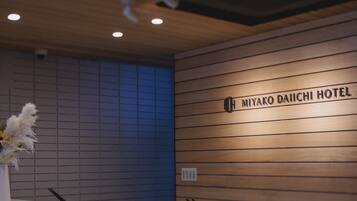 Mostrador de recepción en el Hotel Miyako Daiichi, con un panel de pared de madera y un letrero encima.