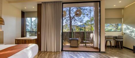 A modern hotel room with a large bed, a desk, and a view of the outdoors.