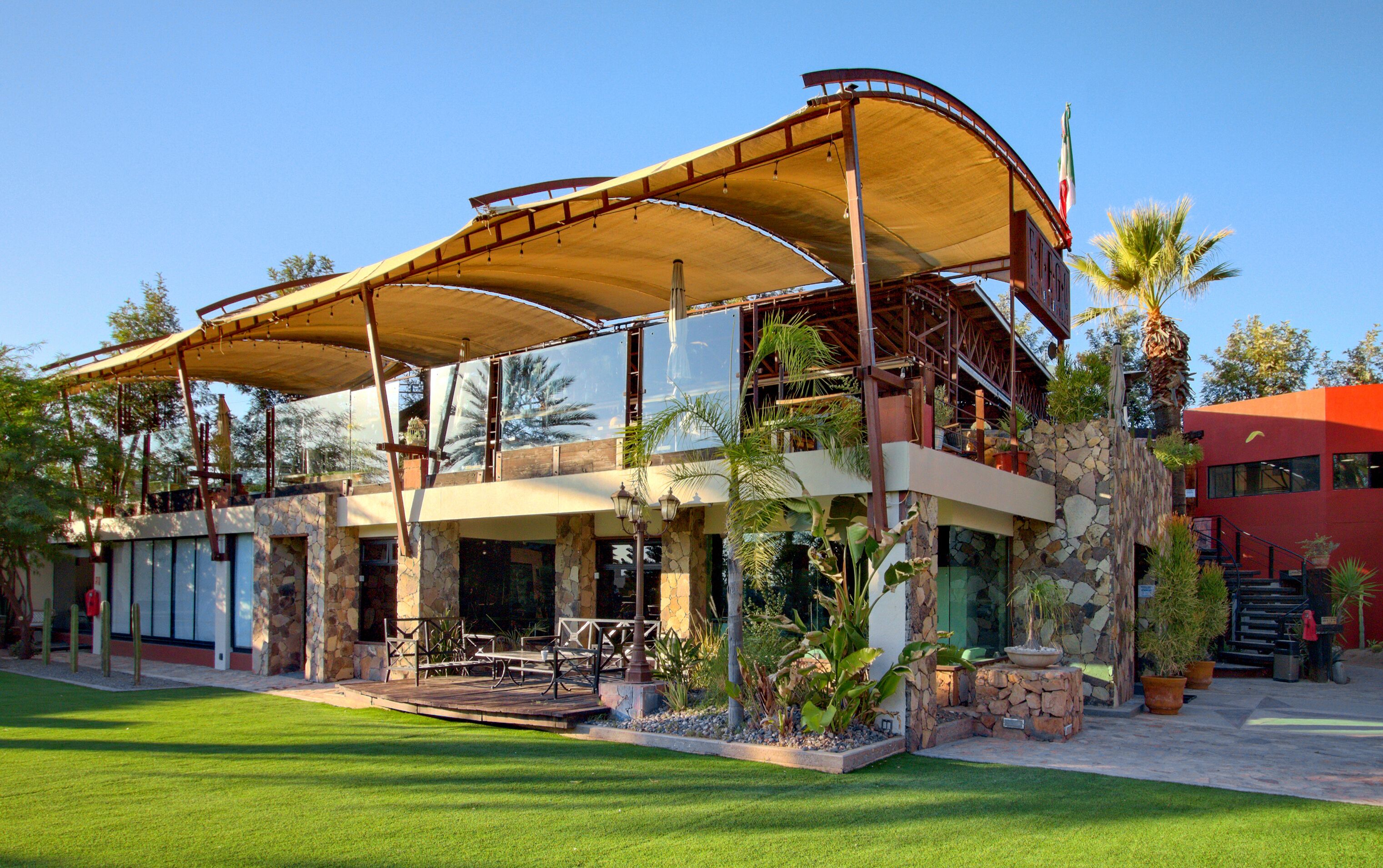 A two-story building with a covered patio, stone walls, and a flag.
