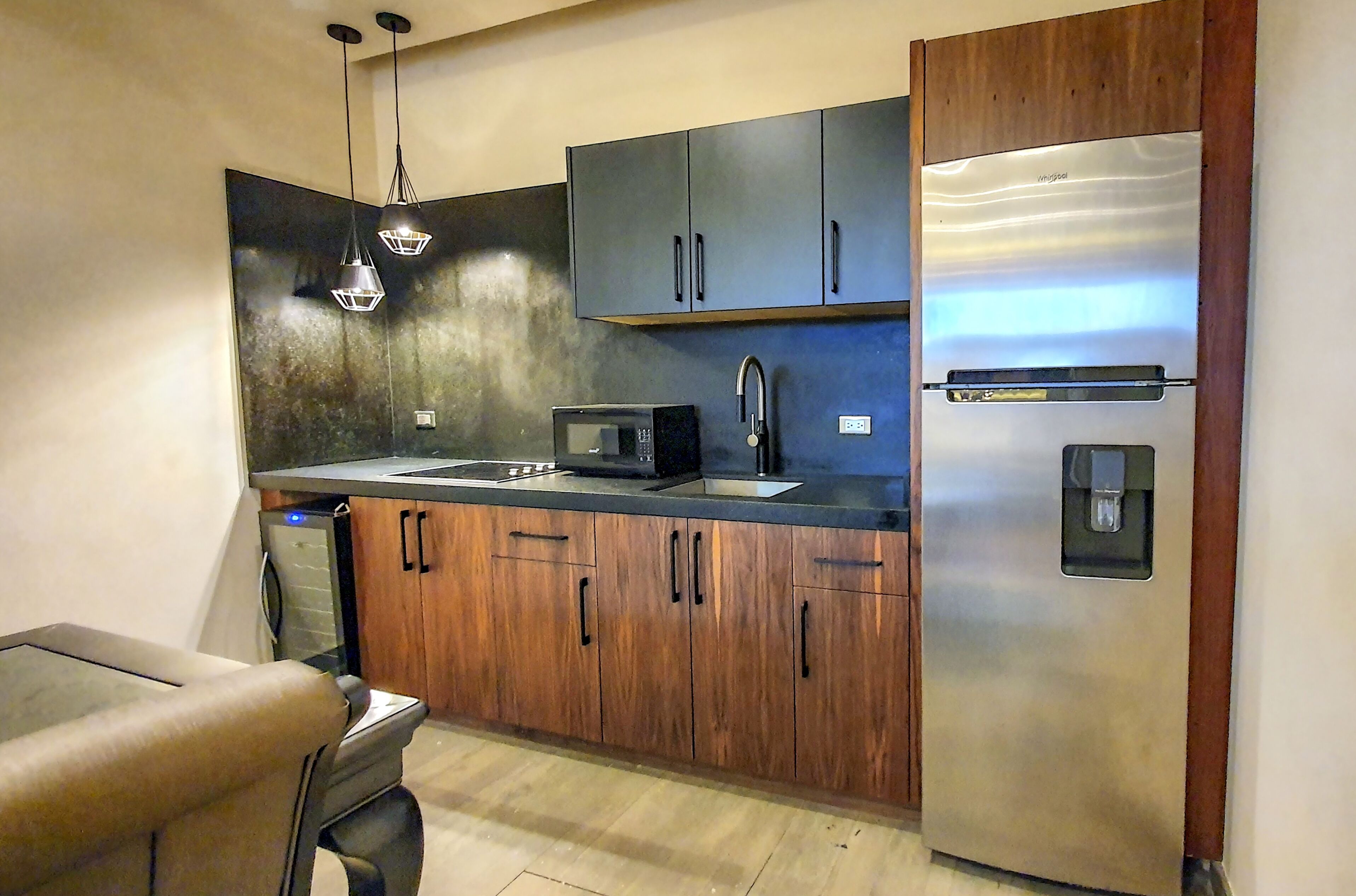 A modern kitchen with wooden cabinets, a stainless steel refrigerator, a microwave, and a sink.