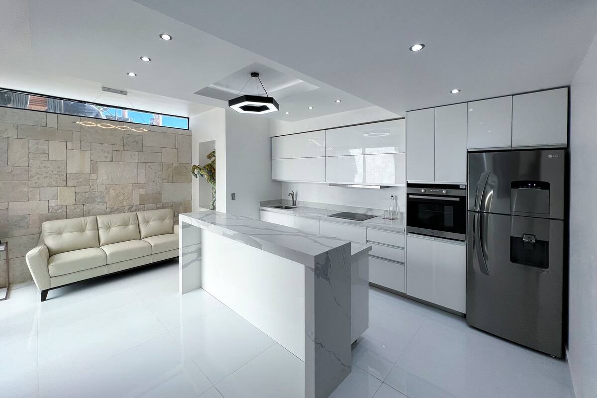 A modern kitchen with a marble island, stainless steel appliances, and a stone accent wall.
