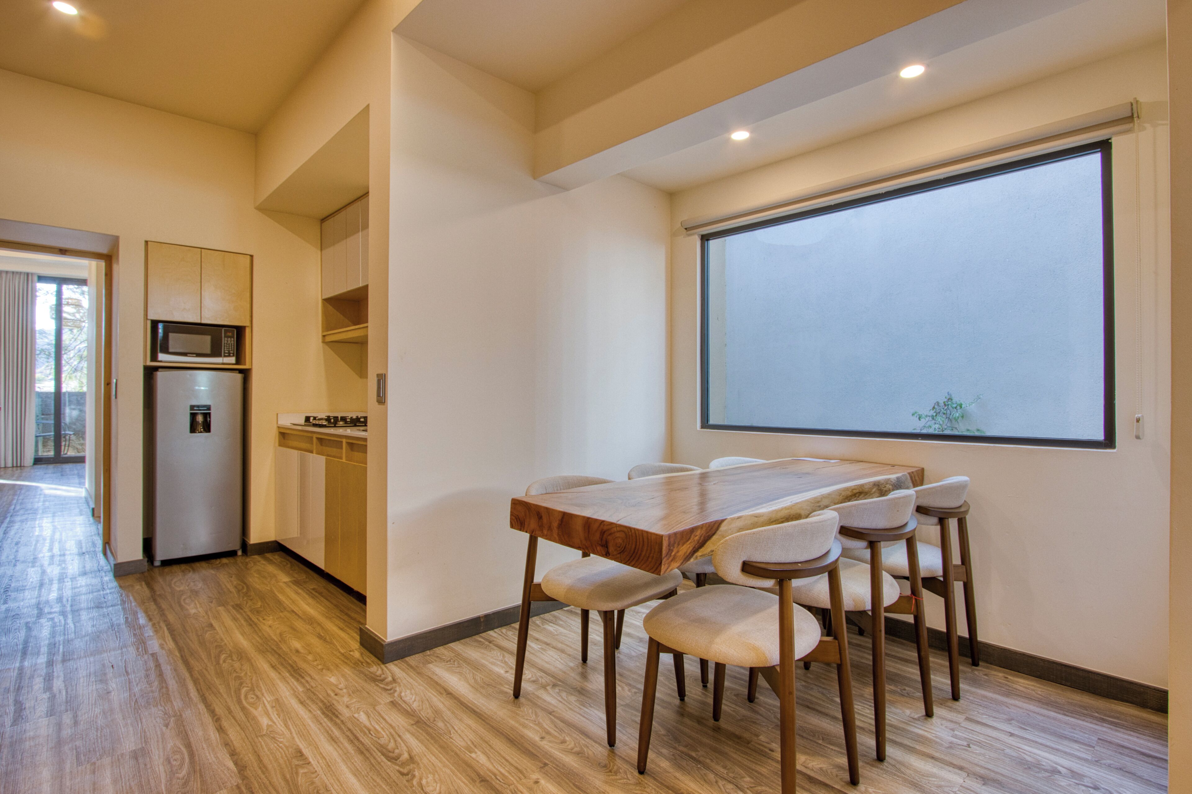 A modern kitchen with a microwave, refrigerator, and wooden cabinets.