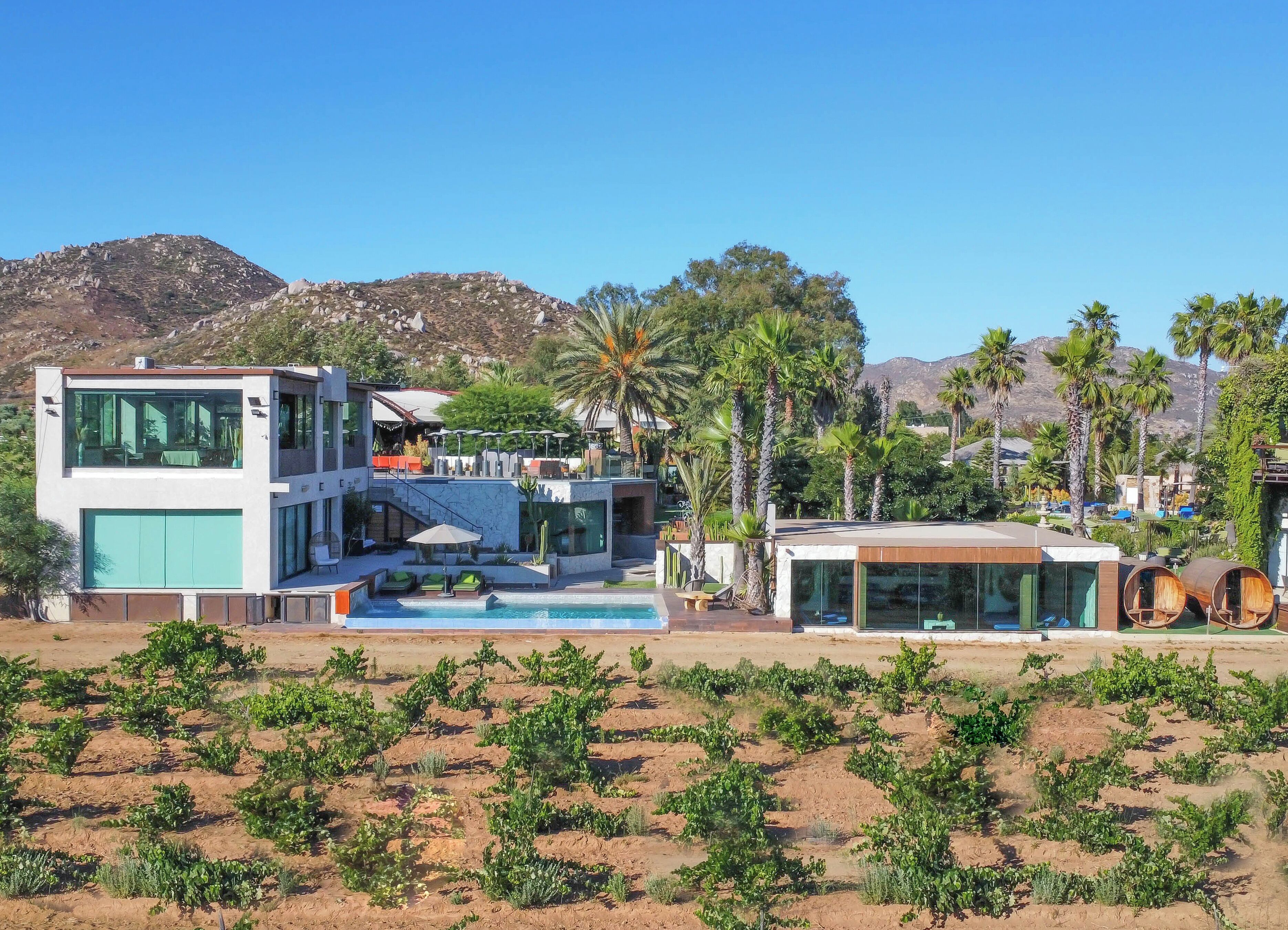 A modern resort with a pool, outdoor seating, and a view of the mountains.