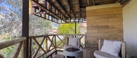 A wooden deck with wicker furniture and a fire pit.