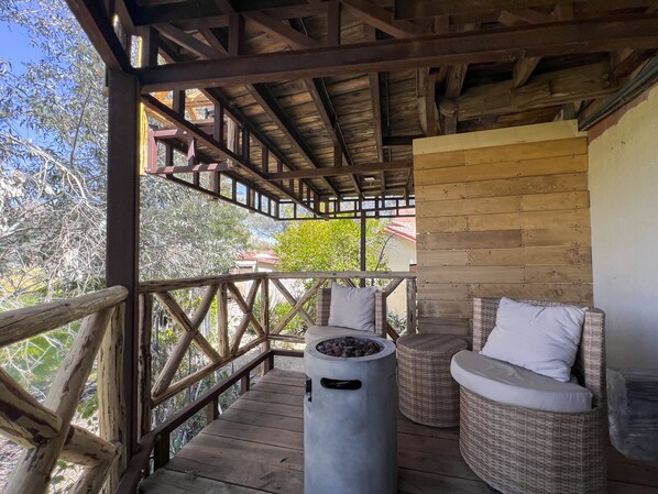 A wooden deck with wicker furniture and a fire pit. - Hotel Boutique Valle de Guadalupe & Spa (Valle de Guadalupe)