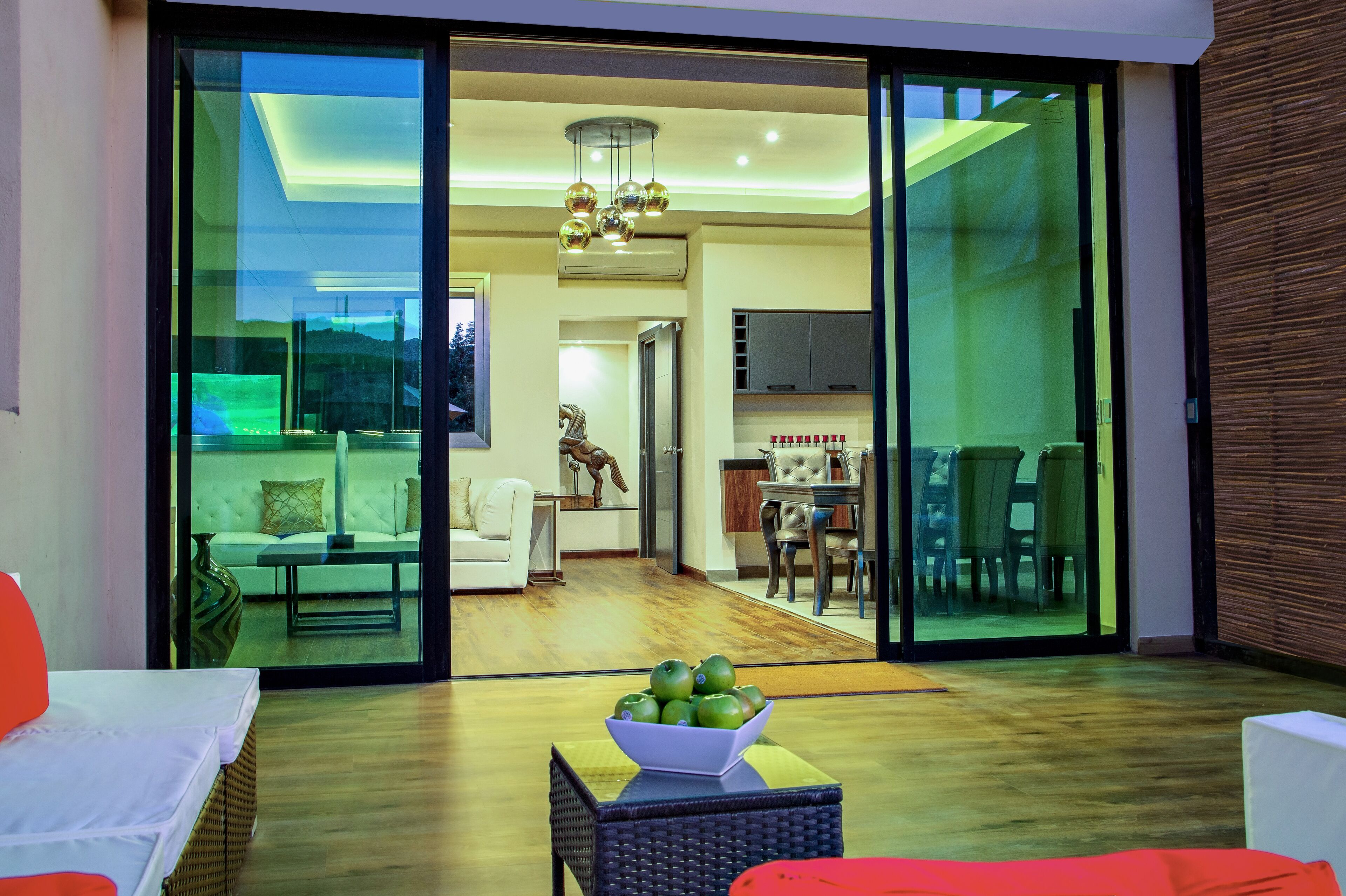 A modern living room with a glass door leading to a dining area and kitchen.