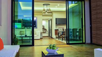 A modern living room with a glass door leading to a dining area and kitchen.