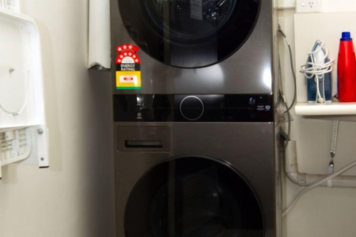 A laundry area with a washing machine and dryer, a water heater, and a shelf with cleaning supplies.