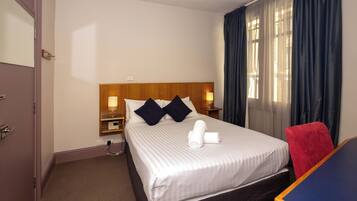 Escritorio, cortinas blackout y tabla de planchar con plancha