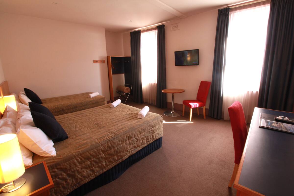 Escritorio, cortinas blackout y tabla de planchar con plancha