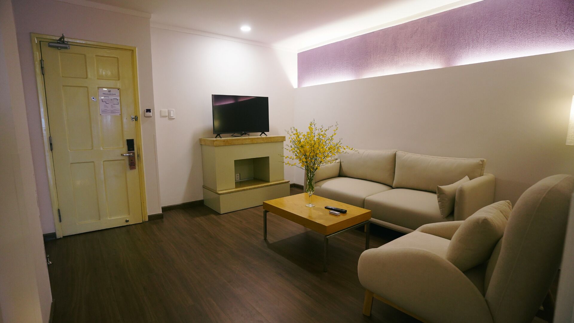 A living room with a sofa, a coffee table, a TV on a stand, and a door with a lock.